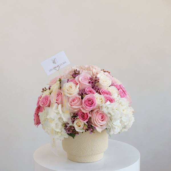 Pink and white rose bouquet in a cream vase