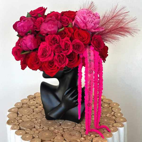 Bouquet of red and pink roses with peonies in a black vase