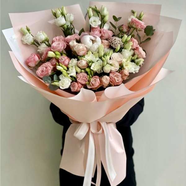 Bouquet of pink and white roses wrapped in pale pink paper