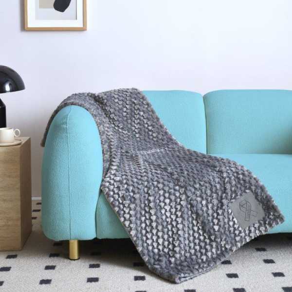 Gray knitted blanket draped over a light blue sofa in a living room