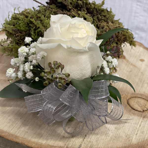 White rose arrangement with baby's breath and silver ribbon on a wood slice