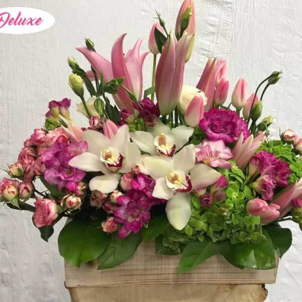 Pink lilies, white orchids, and magenta flowers in a wooden box