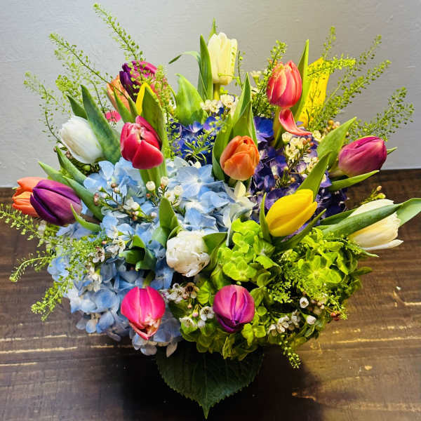 Colorful bouquet of tulips and hydrangeas in a low container