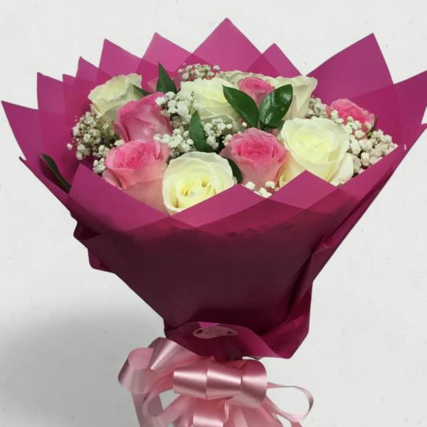 Bouquet of pink and white roses wrapped in magenta paper with a pink ribbon