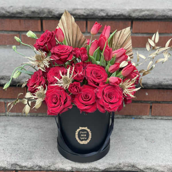 Red roses and pink tulips arranged in a black hatbox
