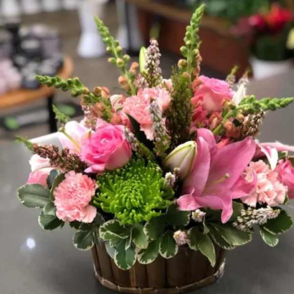 Pink roses and lilies in a wooden basket with green chrysanthemums
