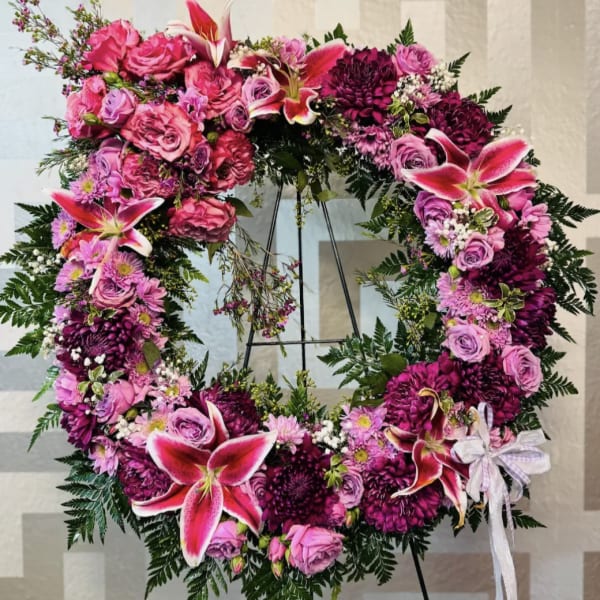 Large circular floral wreath with pink and purple flowers on a stand
