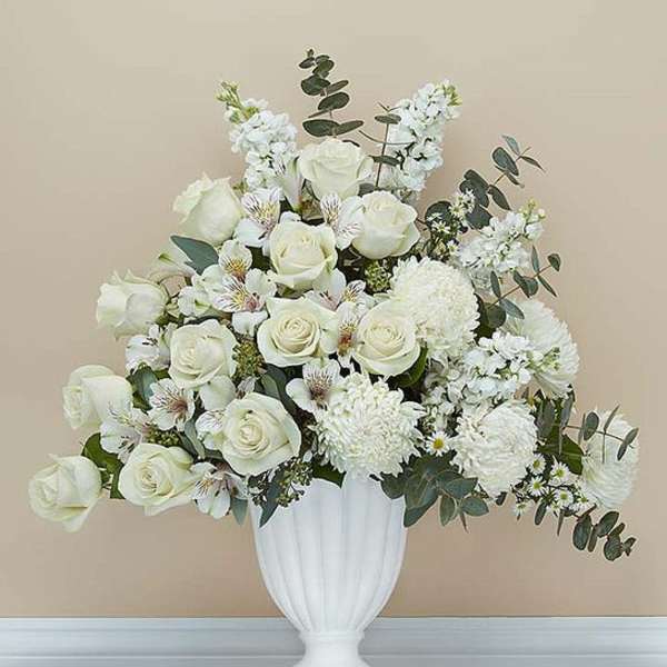 White rose arrangement in a white urn vase