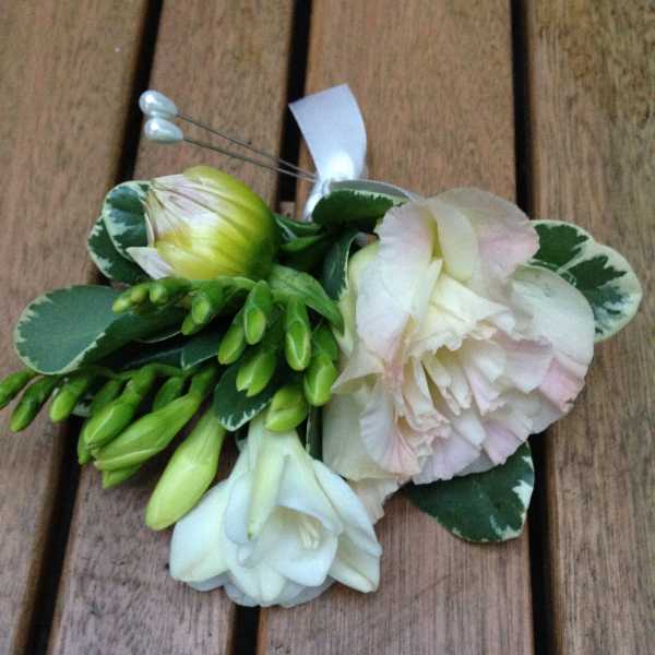 Small floral corsage with white and pale pink blooms on a ribbon tie