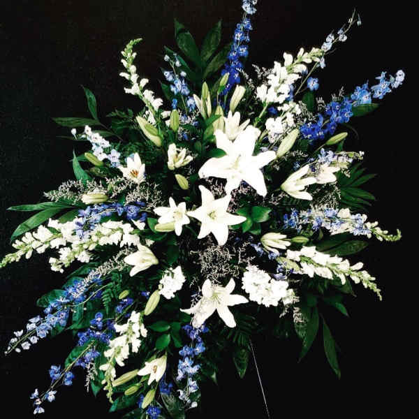 White lilies and blue delphinium in a large spray arrangement