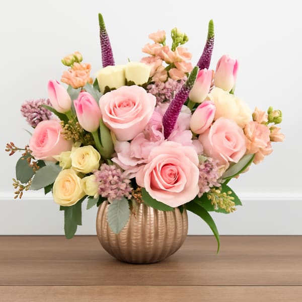 Pink and cream flower arrangement in a ribbed gold vase