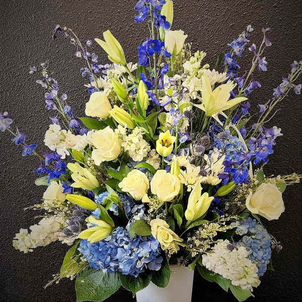 Tall blue and yellow floral arrangement in a white vase