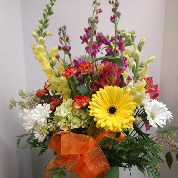 Mixed bouquet in a green vase with a large orange ribbon