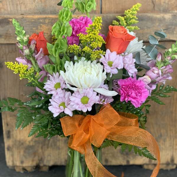 Mixed bouquet in a glass vase with orange ribbon