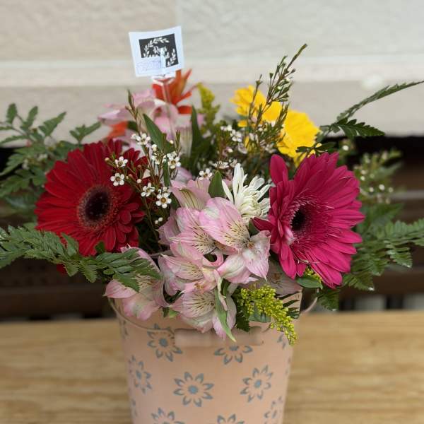 Mixed gerbera daisy bouquet in a pink floral tin