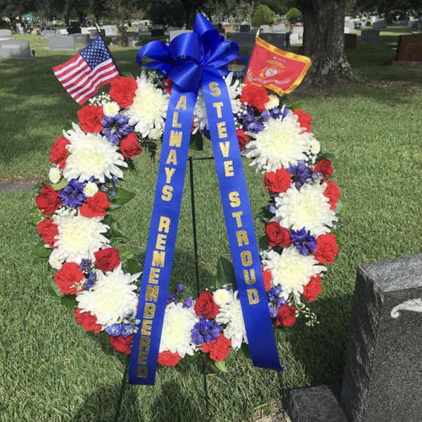 Patriotic funeral wreath with red, white, and blue flowers and ribbons