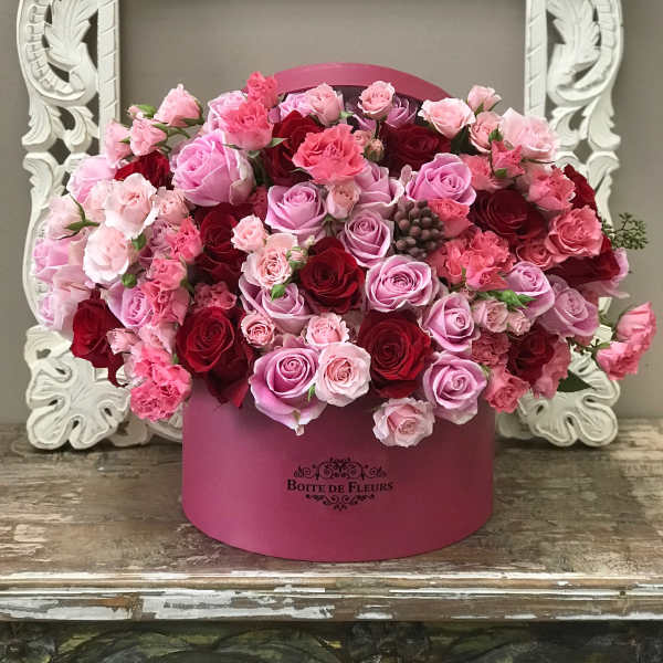 Pink and red roses arranged in a round pink box