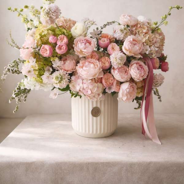 Large pastel bouquet of pink and white flowers in a ribbed white vase