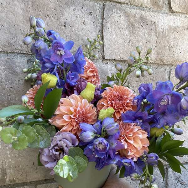 Colorful bouquet in a small gray vase with peach and purple flowers