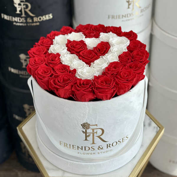 Red and white roses arranged in a heart shape in a white hat box