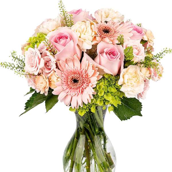 Bouquet of pink roses, gerbera daisies, and cream blooms with green hydrangea in a clear glass vase