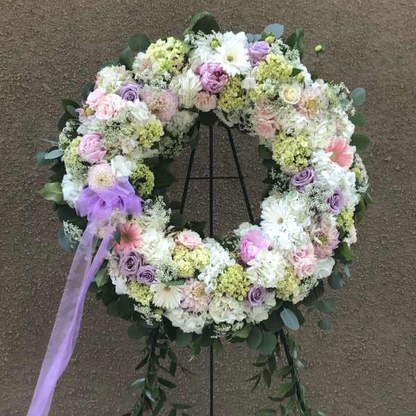 Pastel floral wreath on a stand with a lavender ribbon