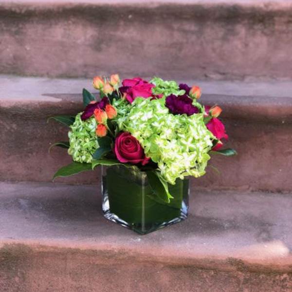 Pink roses and green hydrangeas in a square glass vase