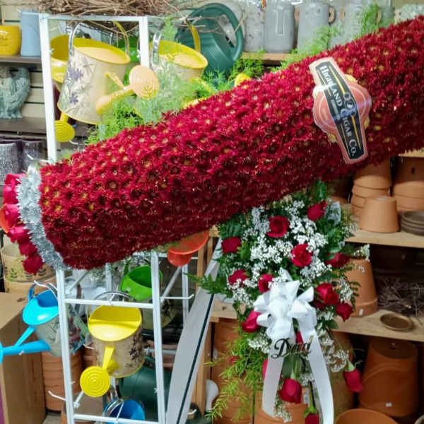 Large red floral standing spray with roses and white ribbon