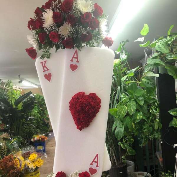 Tall floral arrangement with red roses and white flowers on a white display stand