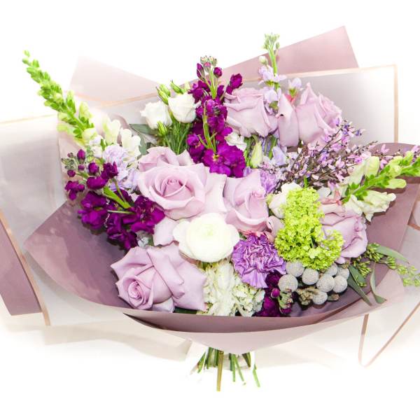 Bouquet of lavender roses and purple flowers wrapped in pink paper