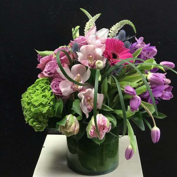 Mixed pink and purple floral arrangement in a glass vase