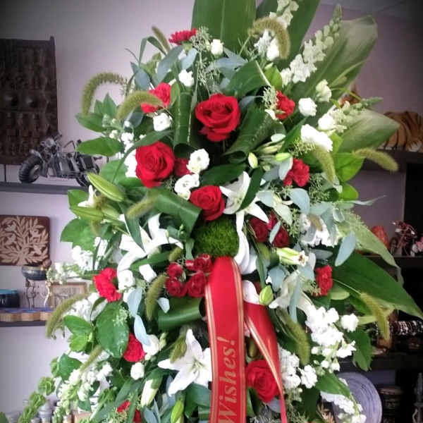Large standing floral spray with red and white flowers on an easel