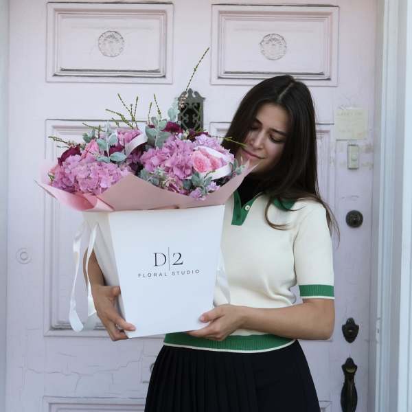 Woman holding a large pink flower bouquet in a white box