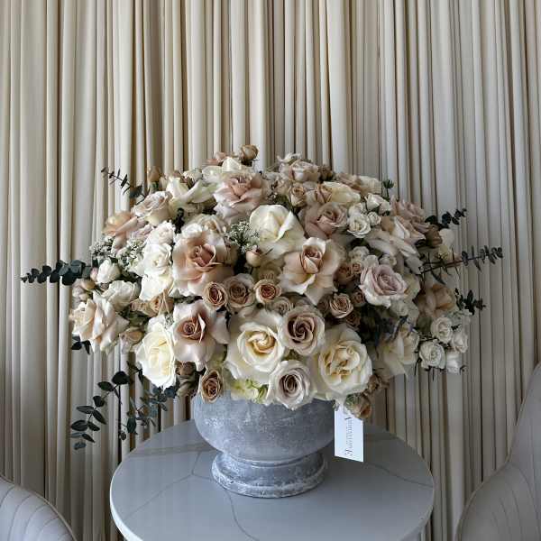 Large cream and blush rose arrangement in a gray urn vase