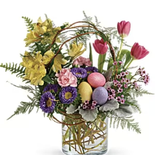 Colorful spring bouquet in a clear glass vase with decorative eggs