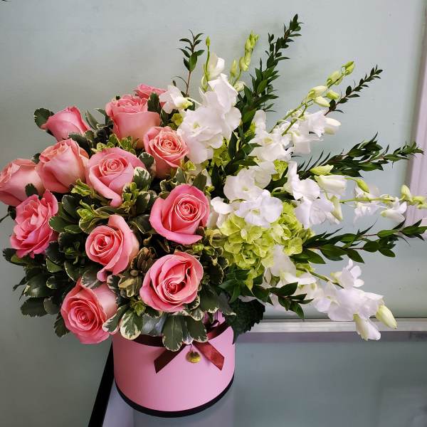 Pink roses and white orchids in a pink hatbox