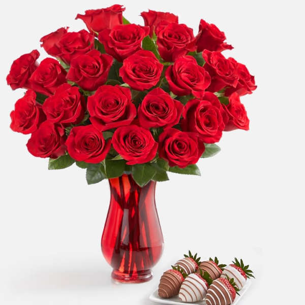 Red roses in a red glass vase with chocolate-covered strawberries on a tray