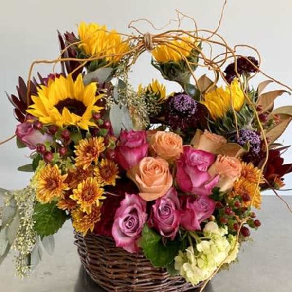 Basket arrangement with sunflowers, roses, and mixed blooms
