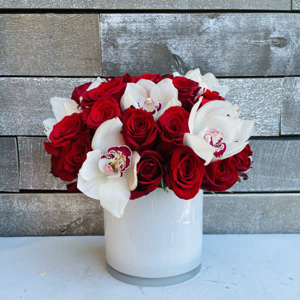Red roses and white orchids arranged in a white vase