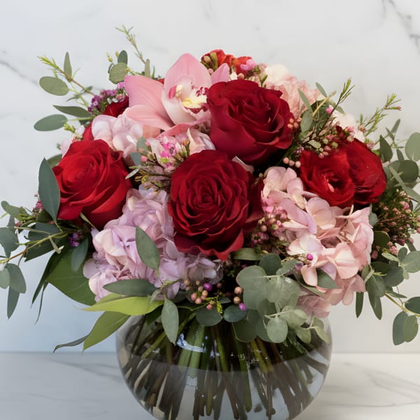 Bouquet of red roses and pink orchids in a glass vase