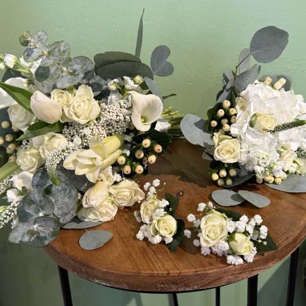 White rose and calla lily bouquets with eucalyptus on a table
