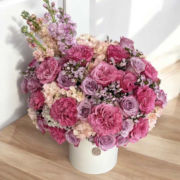 Pink and lavender roses arranged in a white hatbox