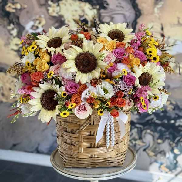 Basket arrangement of sunflowers and multicolored roses