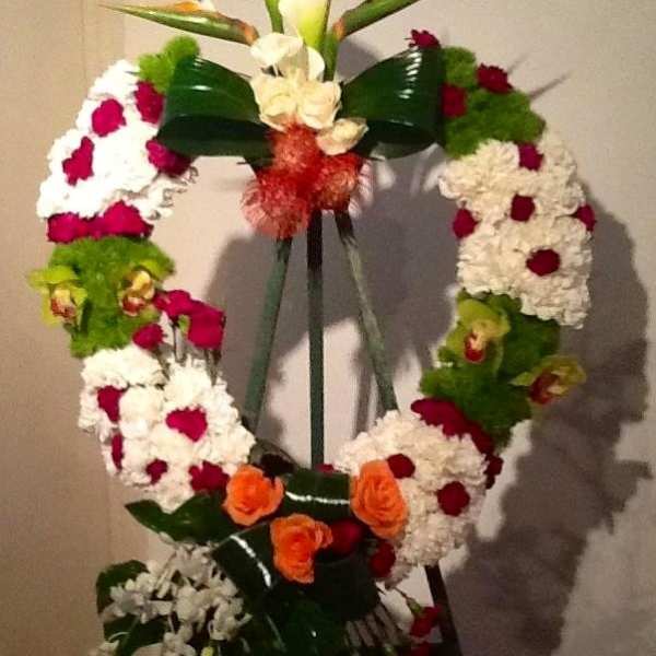 Standing floral wreath with white, red, green, and orange flowers on an easel