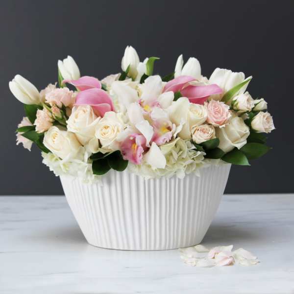 White and pink floral arrangement in a ribbed white vase