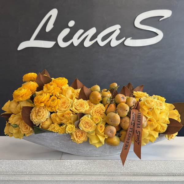 Yellow rose arrangement with fruit in a low gray container