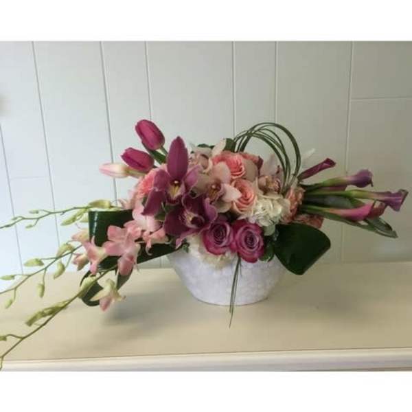 Pink and purple floral arrangement in a white container
