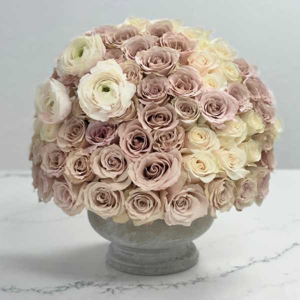 Round bouquet of pale pink and cream roses in a gray pedestal vase