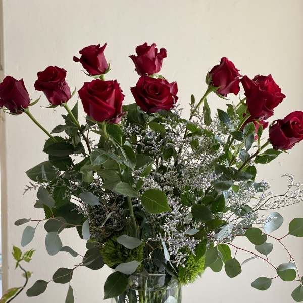 Red roses arranged in a clear glass vase with airy greenery.