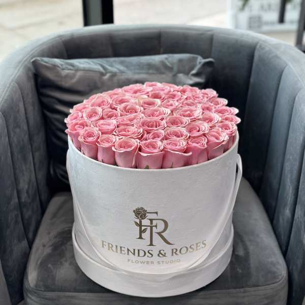 Round box of pink roses on a chair